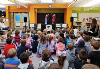 a group of young children watching a puppet show in a school library