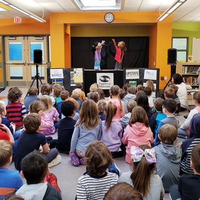 a group of young children watching a puppet show in a school library